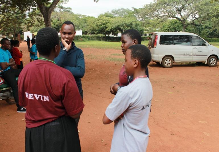 A LeadMinds Africa mentor talking with students outside.
