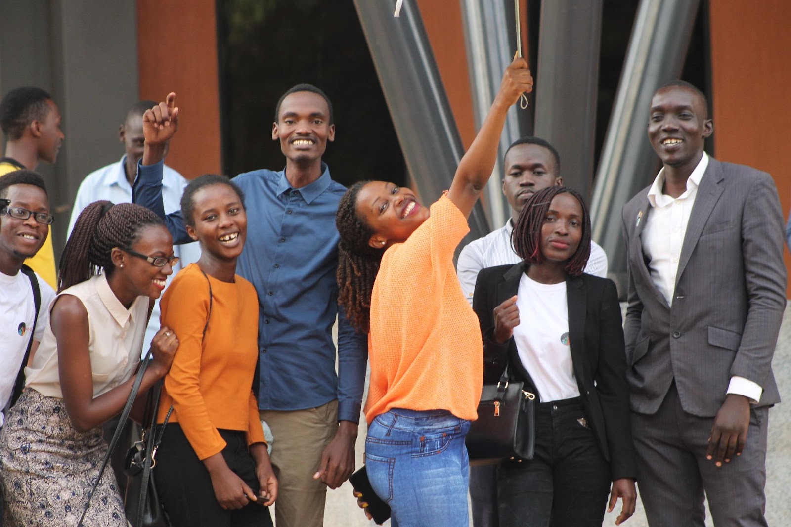 A smiling group of young leaders standing outside.