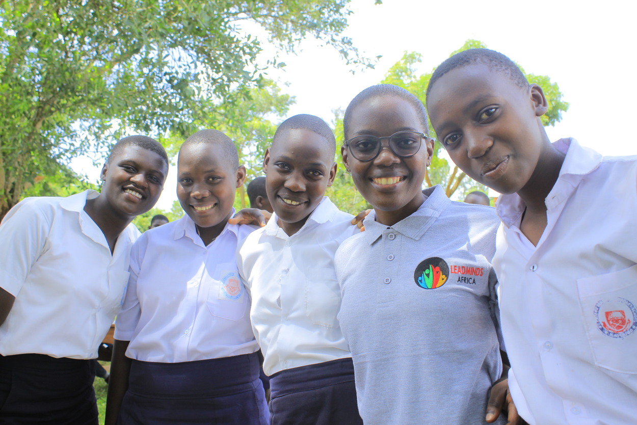 A group of young students smiling outside in uniform.