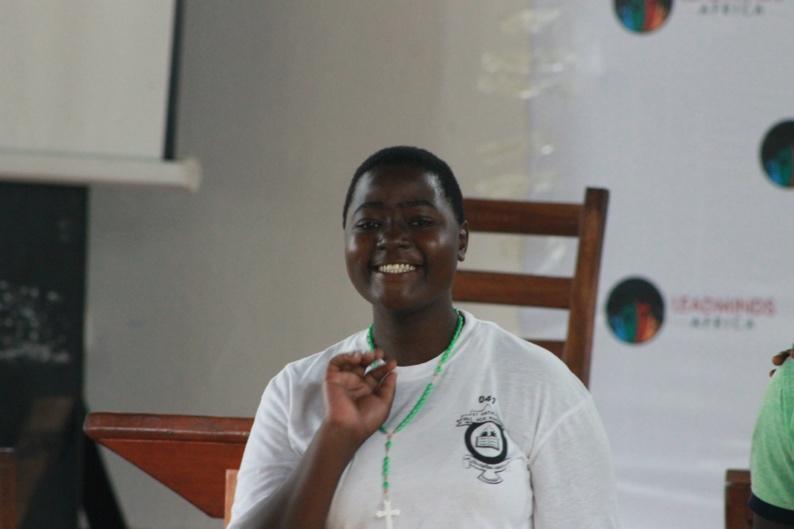 A single student smiles and waves at the camera.