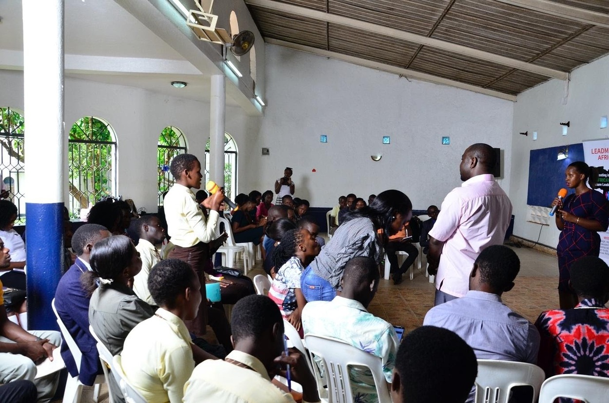 A LeadMinds Africa student stands to ask a question in a group discussion during our Leader's Forum.