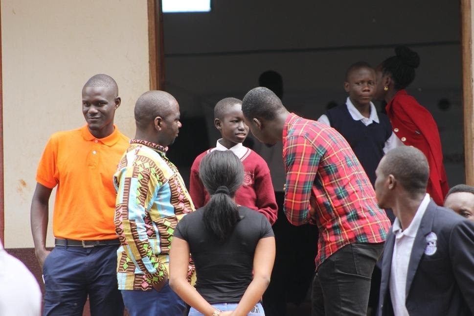 A LeadMinds Africa mentor bends down to offer advice to a young student.