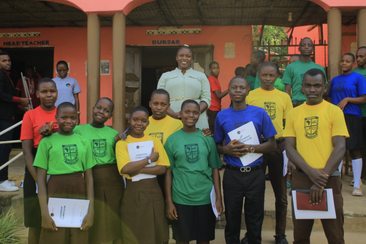 Students in colorful shirts stand in front of their teacher on the stairs.