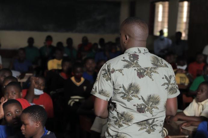 Our founder Enock teaching in front of a group of students.