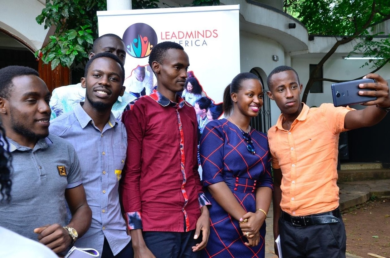 A group of smiling conference attendees takes a selfie.