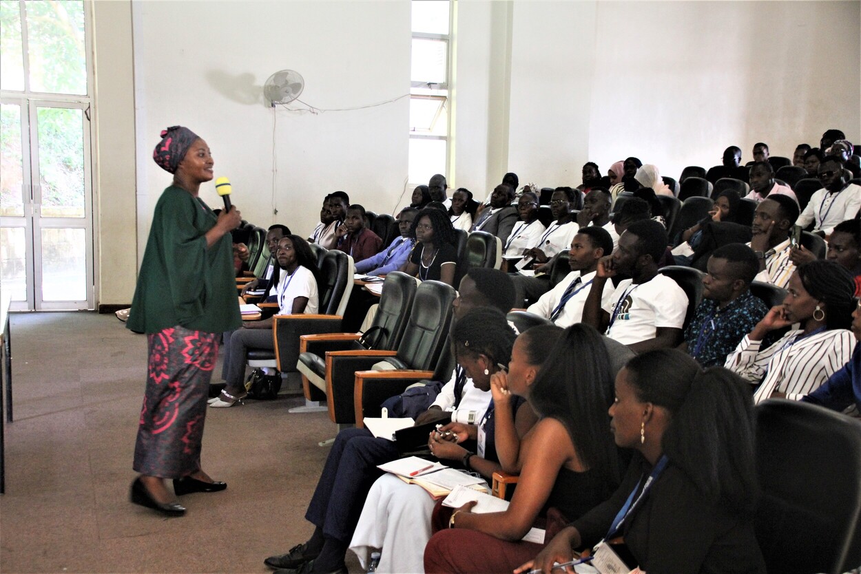 An instructor in Ugandan garb addresses a lecture hall full of student-leaders.